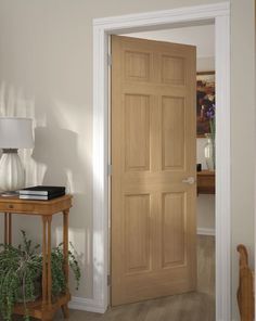 an entry way with a wooden door and potted plant on the table next to it