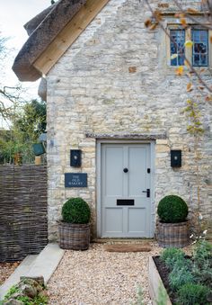 a stone house with potted plants in front of it and a sign on the door