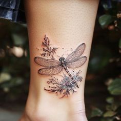 a woman's foot with a dragonfly tattoo on it