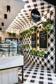 the interior of a restaurant with black and white checkered walls, plants hanging on the wall