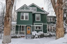 a large green house with snow on the ground and trees in front of it,