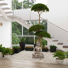 there is a buddha statue in the center of this room with plants and rocks on the floor