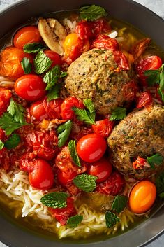 some meatballs and tomatoes are in a bowl with pasta, tomato sauce and basil leaves