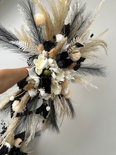 a woman is holding a bouquet with feathers and flowers