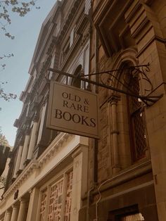 an old and rare book store sign hanging from the side of a building on a city street