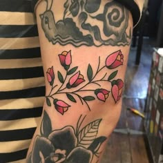 a woman's arm with flowers and clouds tattooed on her left arm, while she is wearing a striped shirt