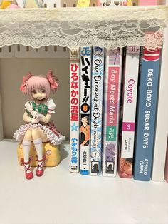 a shelf with some books and a doll on top of it next to other books