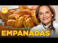 a woman standing in front of a basket full of food with the words empanadas on it