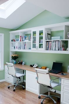 a desk with two chairs and a laptop on top of it in front of bookshelves