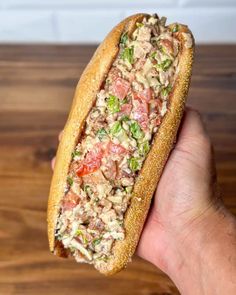 a hand holding a sandwich filled with meat and veggies