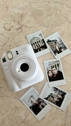 a white camera sitting on top of a table next to pictures and polaroid frames