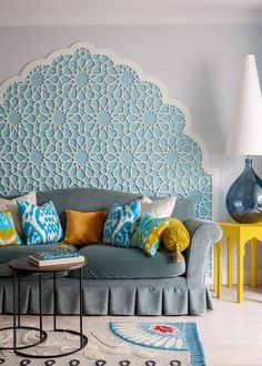 a living room with a blue couch and yellow table in front of the headboard