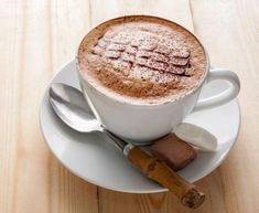 a cappuccino is sitting on a saucer with spoons and cinnamon