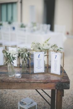 the table is set up with vases filled with flowers and place cards on them