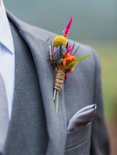 a man wearing a suit and tie holding a boutonniere with flowers on it