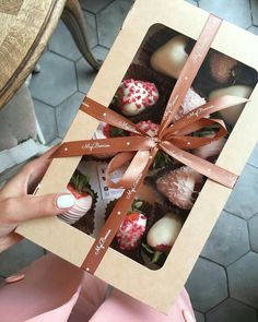 a person is holding a box with chocolates in it that are decorated like strawberries