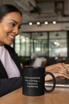 a woman sitting at a table with a laptop and coffee mug in front of her