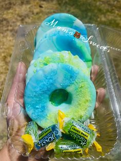 a person holding up a doughnut with blue icing and candies on it