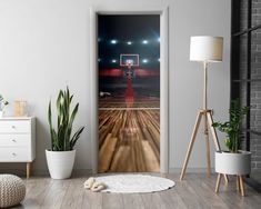 an open door with a basketball court in the middle and lights shining on the floor