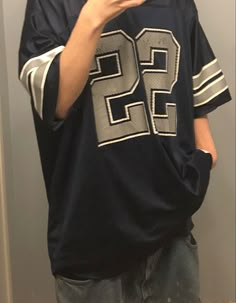 a man taking a selfie with his cell phone in front of him wearing a football jersey