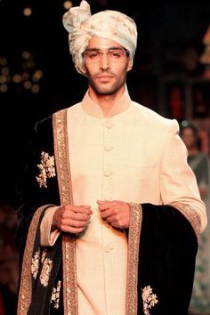 a man in a turban walks down the runway