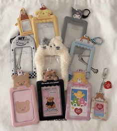 there are many different cell phones and key chains on the white sheet with teddy bears