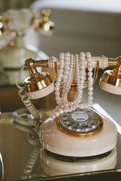 an old fashioned telephone is adorned with pearls