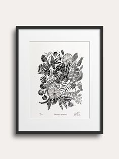 a black and white drawing of leaves in a square frame on a gray wall,