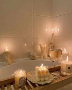 candles sit on a tray next to a bathtub