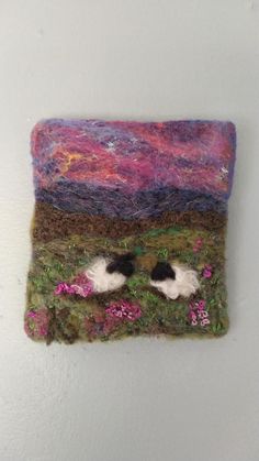 there is a small piece of art made out of wool and yarn with sheep in the grass