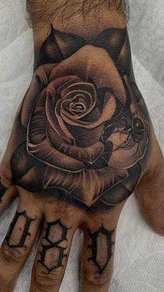 a man's hand with a rose tattoo on it and the letter d in black ink