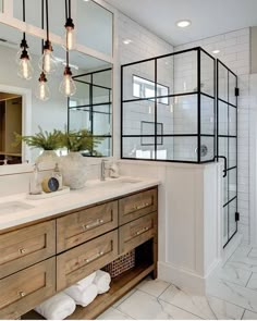 a bathroom with two sinks, mirrors and lights on the wall next to each other