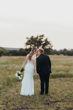 a bride and groom standing in a field