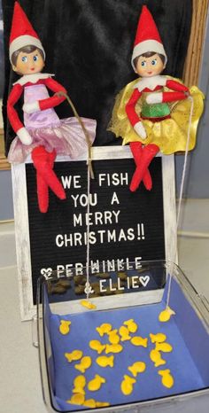 two elfs sitting on top of a sign that says we fish you a merry christmas