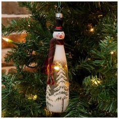 a snowman bottle ornament hanging from a christmas tree with lights on it