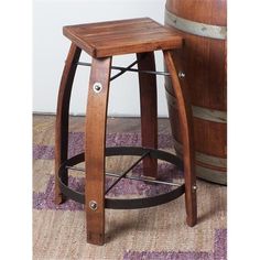 a wooden stool sitting on top of a purple rug next to a barrel filled with wine