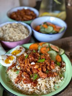 a plate with rice, meat and vegetables on it next to bowls of other food