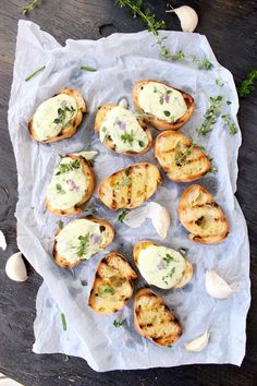 an assortment of appetizers sitting on top of a piece of paper next to garlic and herbs