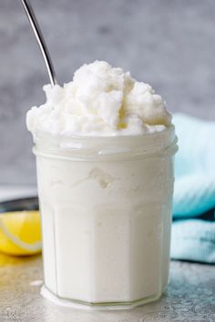 a glass jar filled with whipped cream next to a lemon slice and blue towel on a table