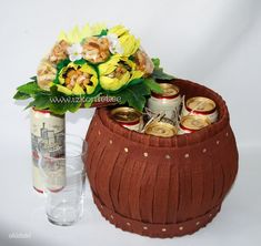 a vase with flowers in it next to an empty beer can and a flower arrangement