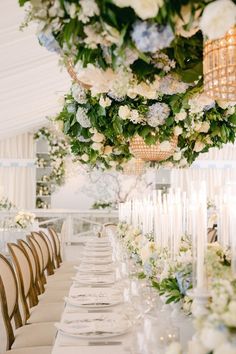 a long table is set with white and blue flowers, candles and centerpieces