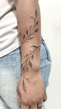 a woman's arm with a tattoo on it and leaves in the middle of her arm