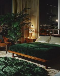 a bedroom with a bed, chair and window overlooking the city lights at night time