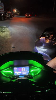 two motorcycles are parked on the side of the road at night with their lights on