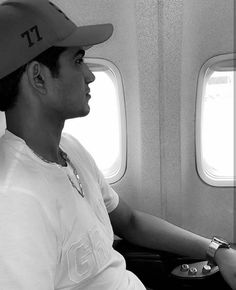 a man sitting on an airplane looking out the window with his hand in his pocket