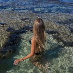 a woman is sitting in the shallow water