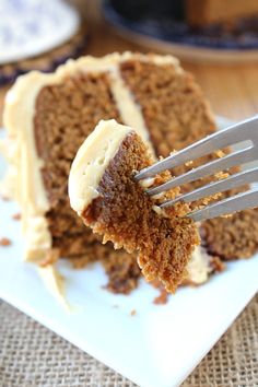 a piece of carrot cake being held up by a fork with the rest of it