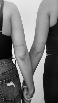 two women holding hands with tattoos on their arms and the words, i love you in cursive writing