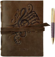 a brown leather journal with music notes on it and a pen next to it,