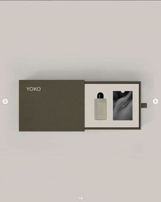 an open box containing two bottles of yoko perfumes, one in grey and the other in white